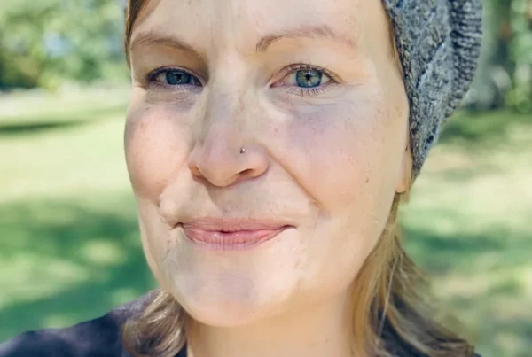 Melissa smiling outdoors in natural light, wearing a knit hat — birth and postpartum doula in New York.