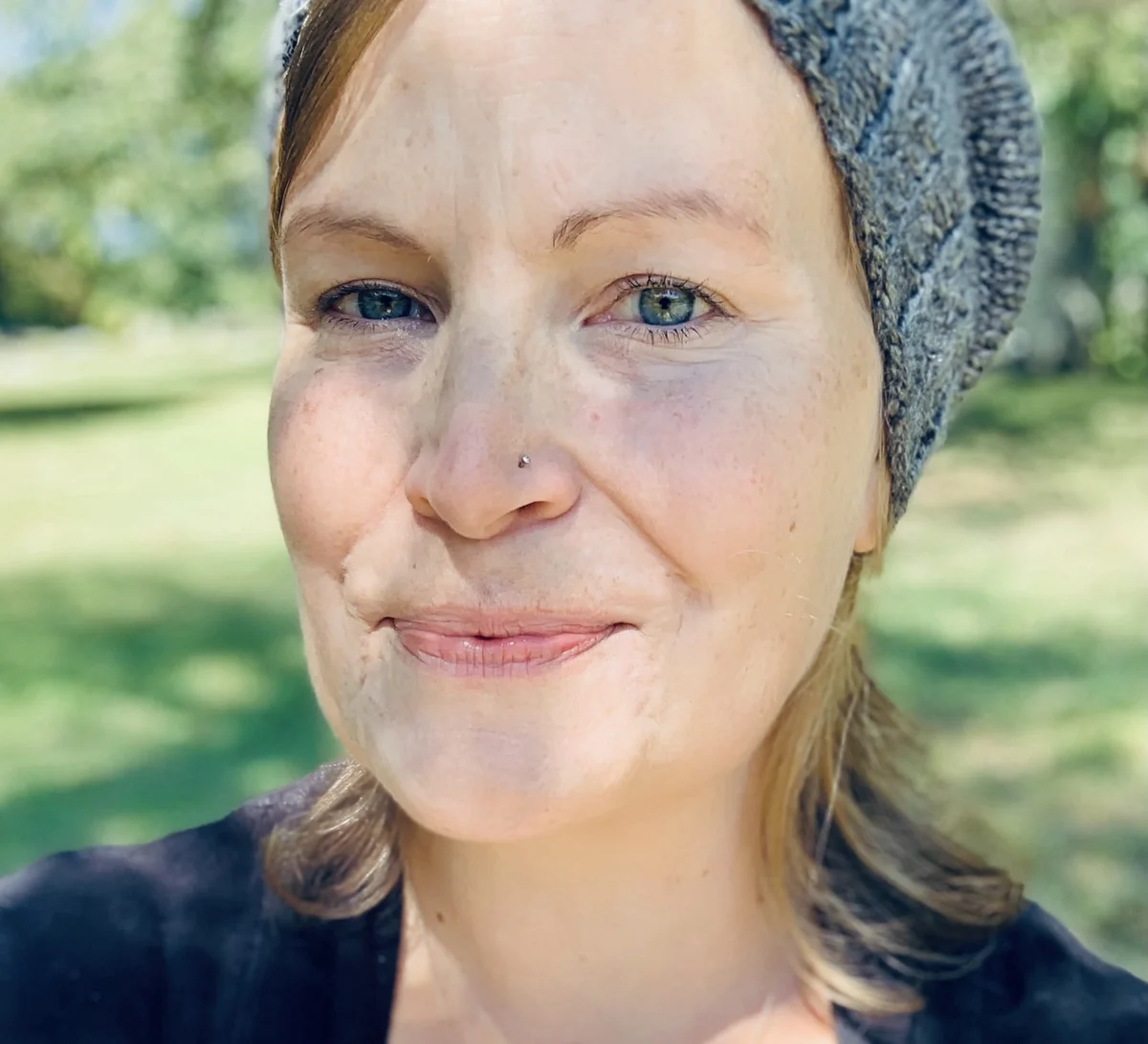 Melissa smiling outdoors in natural light, wearing a knit hat — birth and postpartum doula in New York.