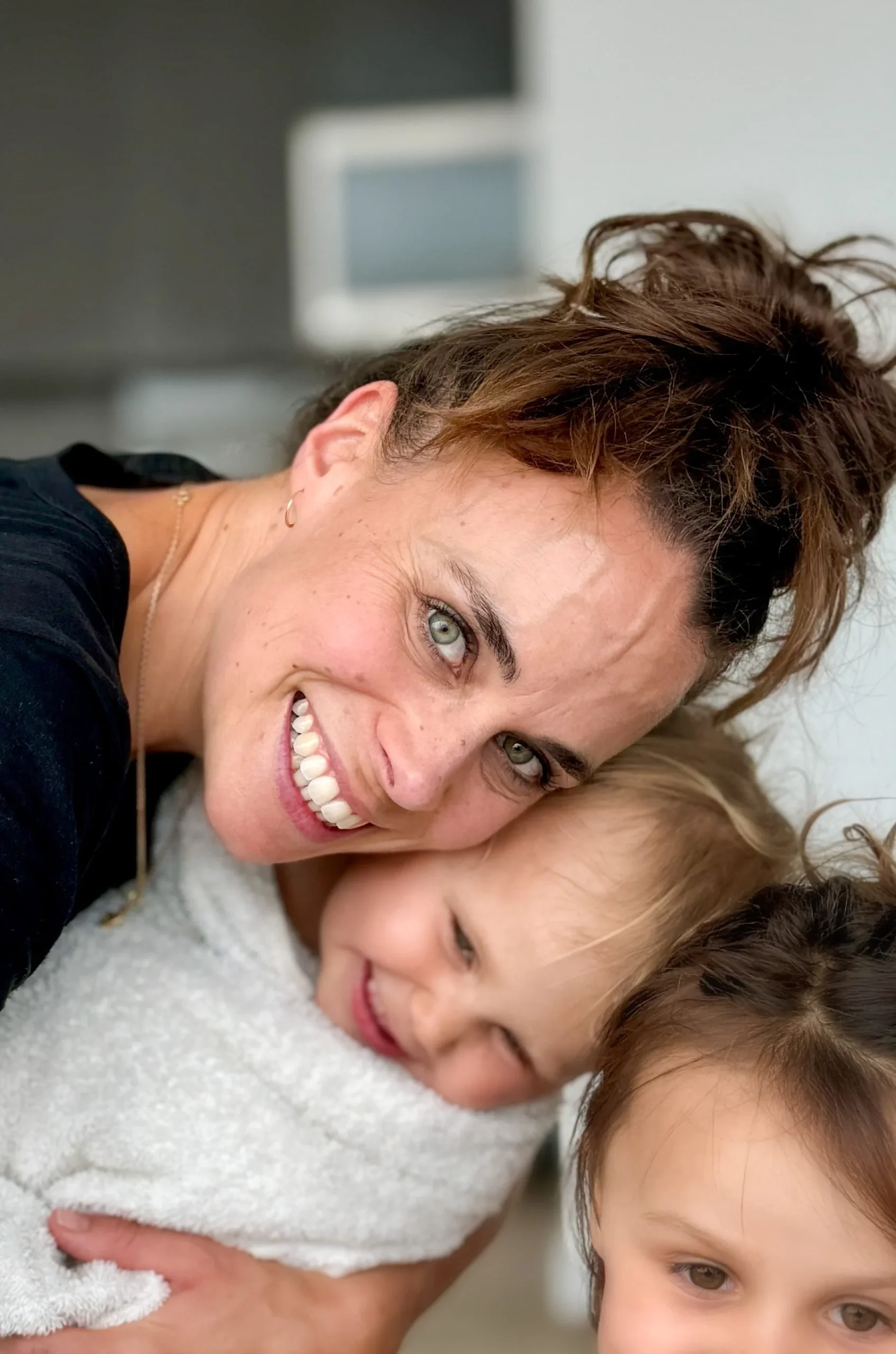Doula Sabina Grabow smiling and holding two young children at home