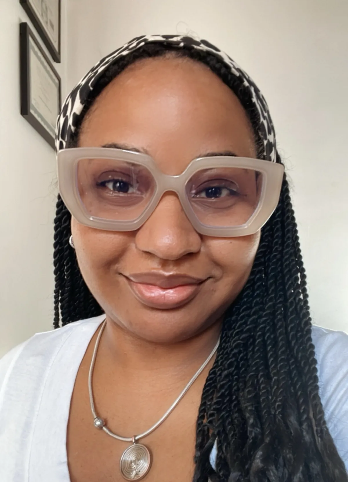 Johanny, a full-spectrum doula with braided hair and oversized translucent glasses, smiling warmly.