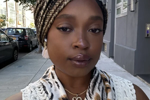 Sierra, certified full-spectrum doula in NYC, standing outdoors and smiling softly.