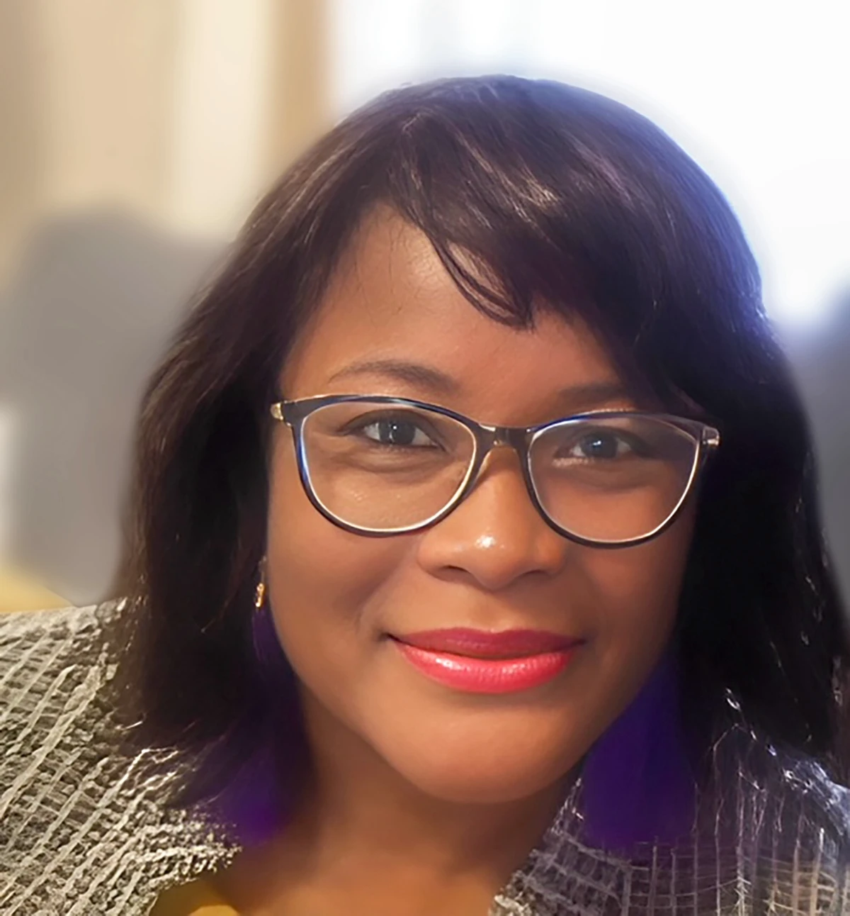 Professional portrait of Tracy, a certified postpartum doula in New York, smiling warmly while wearing glasses.