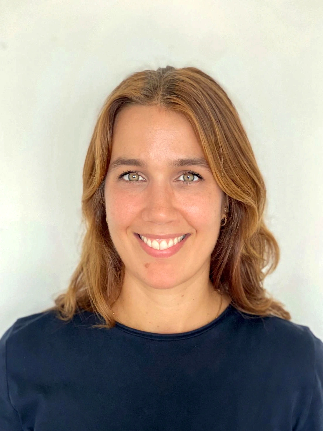 Portrait of Nina, a certified postpartum doula and yoga instructor based in New York City, smiling in a natural light setting.