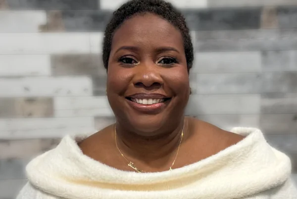 Portrait of Isioma, a certified postpartum doula based in Brooklyn, smiling in a calm, neutral setting.