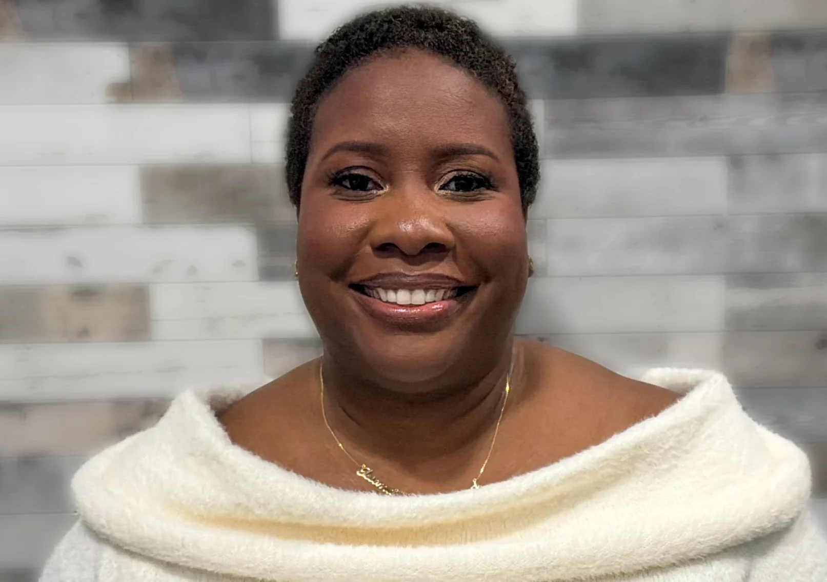 Portrait of Isioma, a certified postpartum doula based in Brooklyn, smiling in a calm, neutral setting.